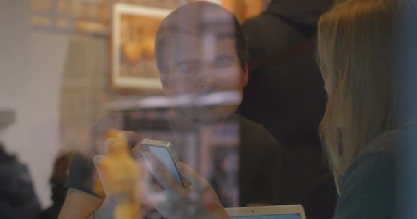 Kobieta i mężczyzna mają dyskusja w restauracji przy użyciu smartphone - Materiał filmowy, wideo