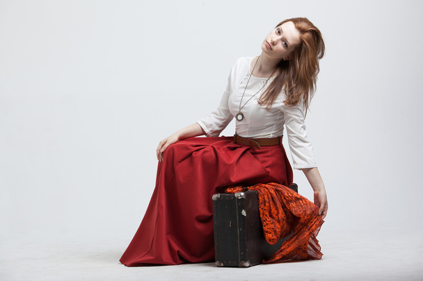 Woman sitting on suitcase, isolated, white background - Foto, afbeelding
