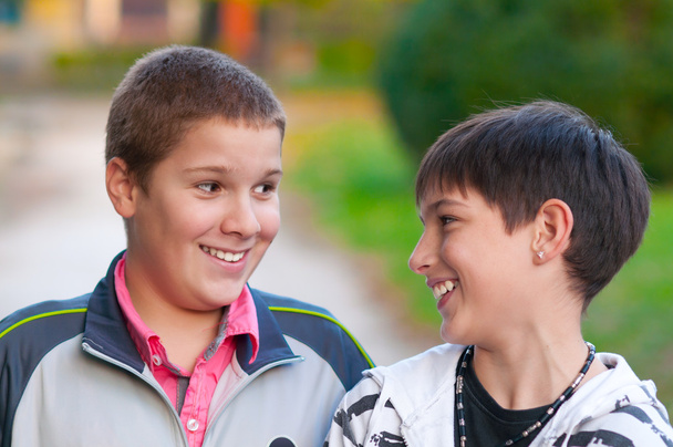 Двоє хлопчиків-підлітків сміються і жартують в парку в прекрасний осінній день
 - Фото, зображення
