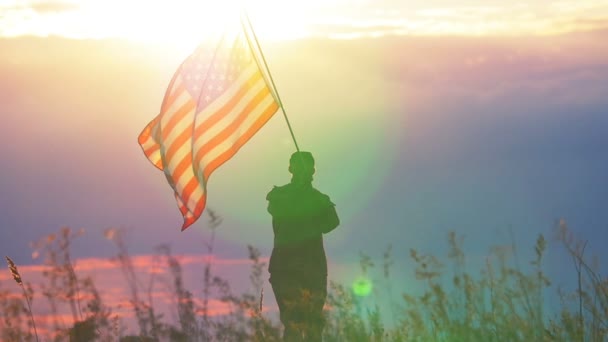 Soldaat golven Amerikaanse vlag tegen zonsondergang hemel. Slow motion scène - Video
