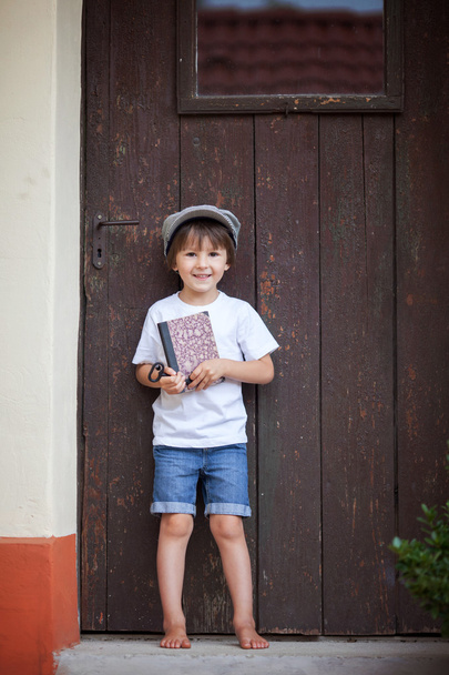Cute little child, boy, holding big metal key and a book, willin - Foto, Imagen