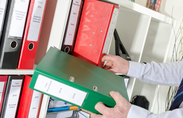 Businessman taking binders from a shelf - Photo, Image