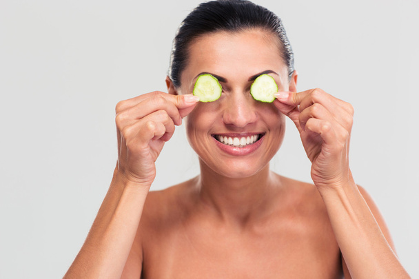 Happy woman covering her eyes with cucumber - Valokuva, kuva