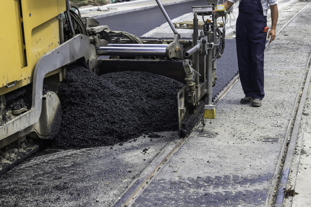 Trabajador y máquina de pavimentación de asfalto
 - Foto, imagen