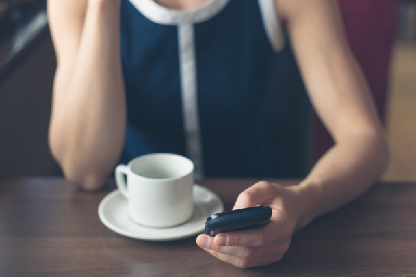 Vrouw met koffie en gebruikend smartphone - Foto, afbeelding