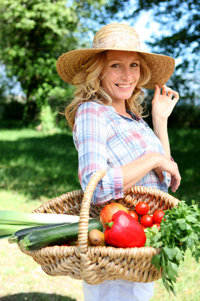 Pretty woman with a straw hat and basket of vegetables. - Zdjęcie, obraz