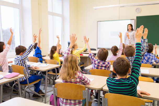group of school kids raising hands in classroom - Фото, зображення