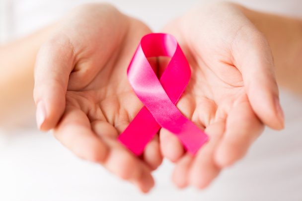 close up of hands and pink cancer awareness ribbon - Φωτογραφία, εικόνα