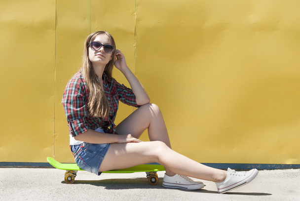 Menina elegante sentada em um skate
. - Foto, Imagem