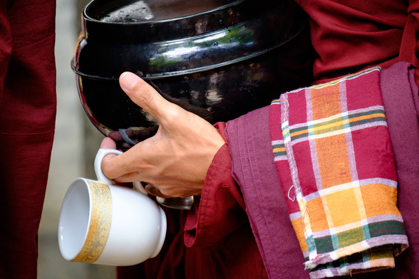 Барвисті деталі буддійських рук ченця, що тримають миску і чашку
 - Фото, зображення