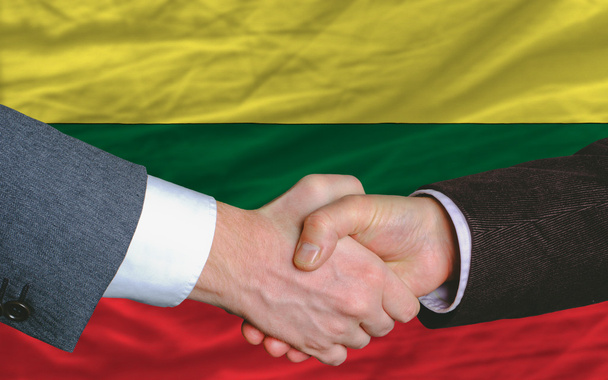 Uomini d'affari stretta di mano dopo un buon affare di fronte alla bandiera lituania
 - Foto, immagini