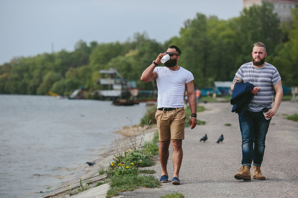 Two men walk and drink coffee - Φωτογραφία, εικόνα