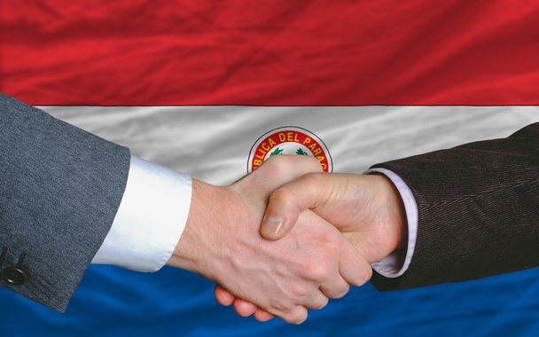 Businessmen handshake after good deal in front of paraguay flag - Photo, Image