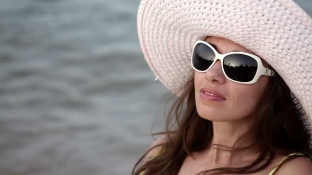 bela mulher em um chapéu e óculos de sol banhos de sol na praia
 - Filmagem, Vídeo