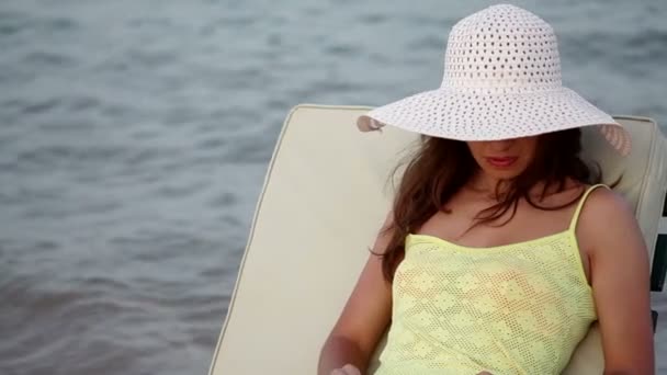 piękna kobieta w kapelusz i okulary opalanie na plaży - Materiał filmowy, wideo
