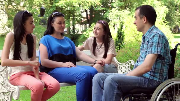 Mladý muž na invalidním vozíku s rodinou v parku - Záběry, video