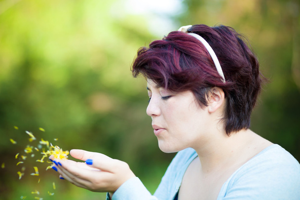 Жінка дме пелюстки квітки - Фото, зображення