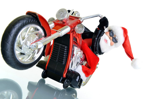 Joulupukki seisoo moottoripyörän valkoisella taustalla
 - Valokuva, kuva