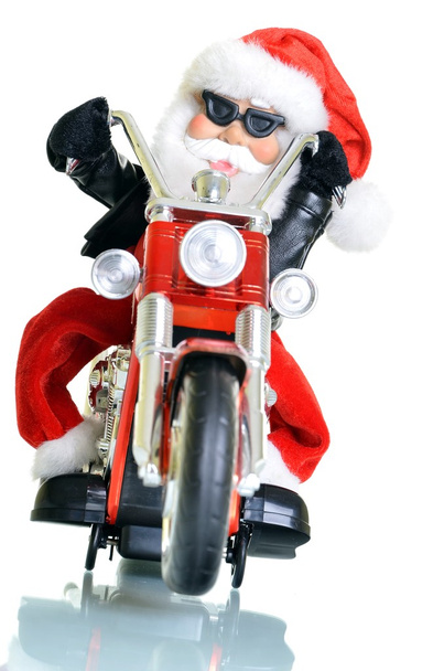 Joulupukki seisoo moottoripyörän valkoisella taustalla
 - Valokuva, kuva