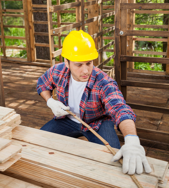 Construction Worker Measuring Wooden Plank At Site - Valokuva, kuva