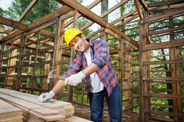 Confident Construction Worker Hammering Nail On Wooden Plank - Fotó, kép