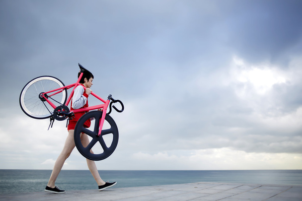 mujer sosteniendo su bicicleta de peso ligero
 - Foto, Imagen