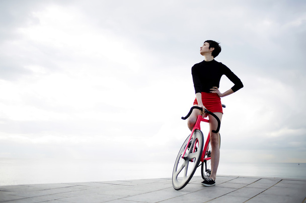 junge Frau steht mit ihrem modernen Fahrrad - Foto, Bild