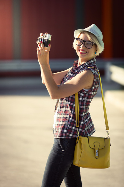 hipster girl walking on street and making photo of retro camera - Photo, Image