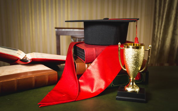 graduation hat, red ribbon and golden cup for first place - Photo, Image