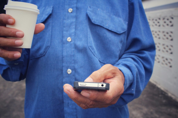 Man drinken koffie papier beker met slimme telefoon - Foto, afbeelding