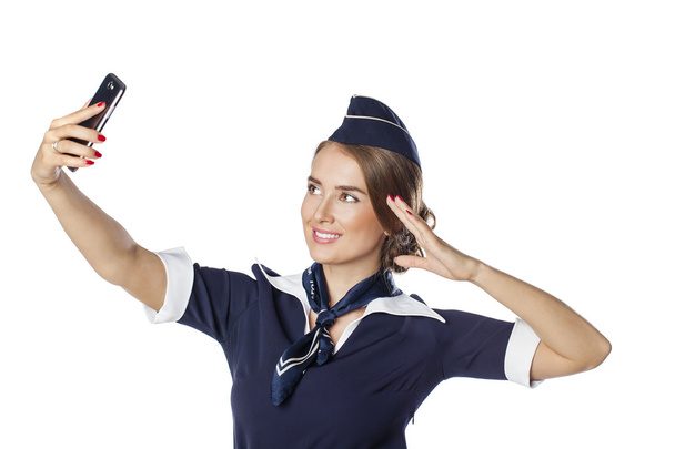 Happy young stewardess holding a smart phone isolated on white b - Zdjęcie, obraz