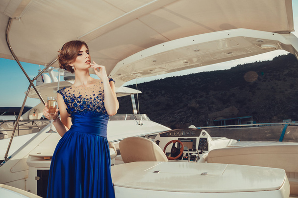 Beautiful young sexy girl in a dress and makeup, summer trip on a yacht with white sails on the sea or ocean - Foto, afbeelding