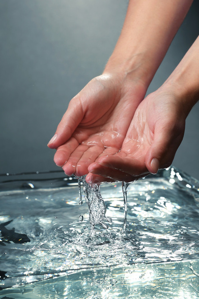 Female hands with water splashing on dark background - Fotó, kép