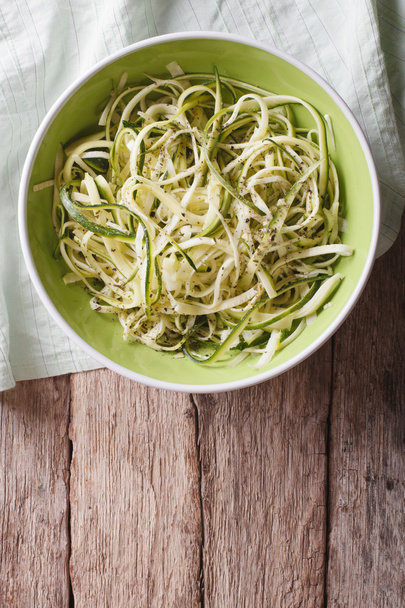 Useful raw zucchini pasta in a bowl close up. vertical top view - Zdjęcie, obraz