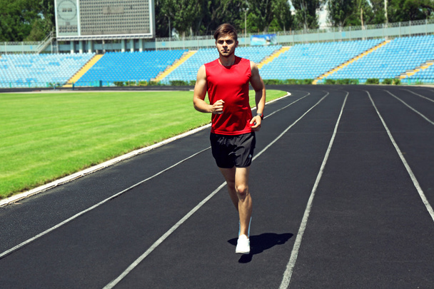 Młody człowiek jogging na stadion - Zdjęcie, obraz