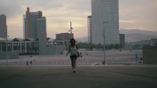 Meisje met een skate wandelen in Barcelona tijdens zonsondergang - Video