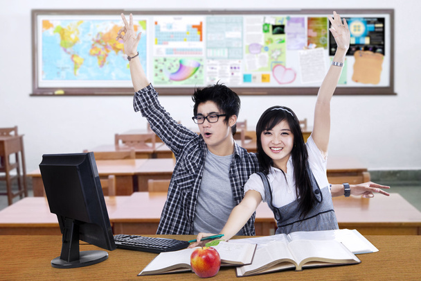 Deux étudiants excités lèvent la main ensemble en classe
 - Photo, image