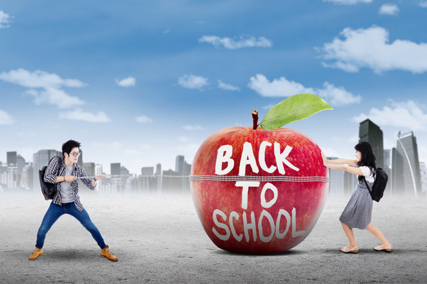 Δύο μαθητές και μήλο με κείμενο της επιστροφή στο σχολείο - Φωτογραφία, εικόνα