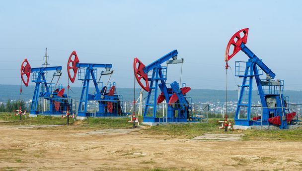 olaj- és gázipari ágazat. olaj szivattyú jack egy olajmező a munkáját. fehér felhők és a kék ég. Olajkút szivattyú. olaj- és gázipari ágazat. olaj szivattyú aljzatát egy olajmező munkájának. - Fotó, kép