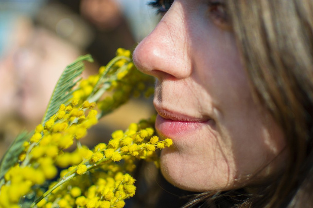 Close up portrait of a girl with sprig of mimosa - Photo, Image