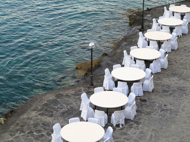 Restaurante al aire libre cerca del mar, sillas blancas y mesas
 - Foto, imagen