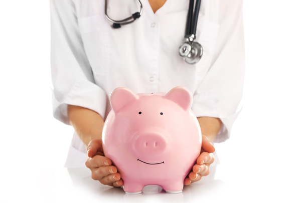 Doctor holding pink piggy bank - Zdjęcie, obraz