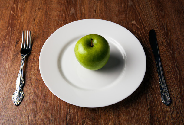 стіл призначень і свіже зелене яблуко на білій тарілці
 - Фото, зображення