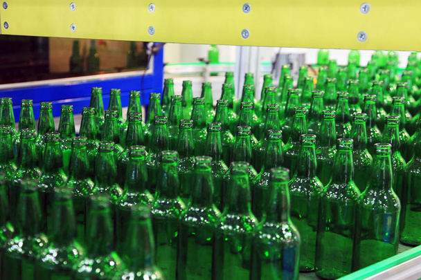 Πολλά μπουκάλια στον ιμάντα μεταφοράς στο εργοστάσιο - Φωτογραφία, εικόνα