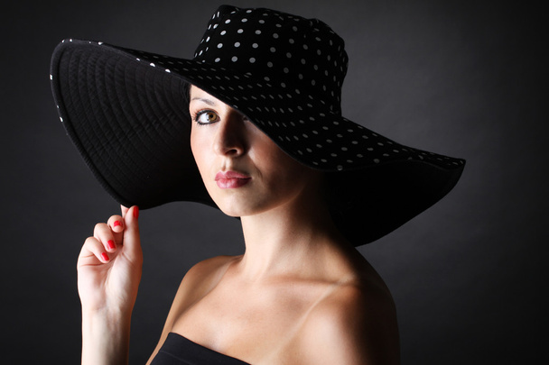 Young and pretty woman with hat on black background - horizontal - Foto, Imagem