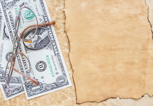 dollar bankbiljetten en bril op oude papier achtergrond - Foto, afbeelding