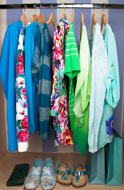 Цветная женская одежда на вешалках в гардеробе
 - Фото, изображение