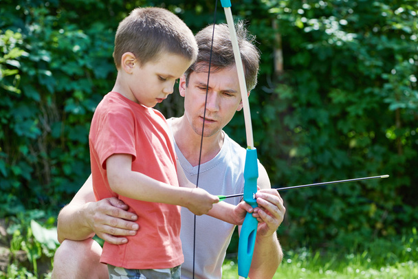 Father is learning his son to shoot from bow - Photo, Image