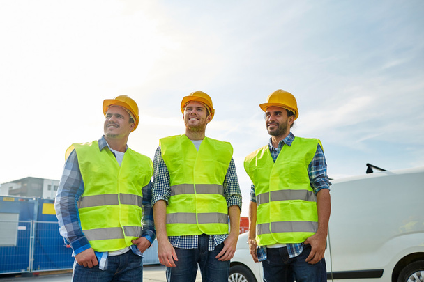 happy male builders in high visible vests outdoors - Foto, Bild
