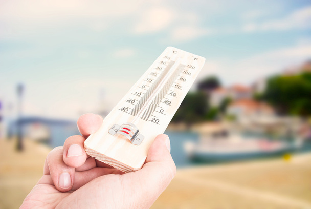 Hand holding thermometer on city with lake background - Photo, Image